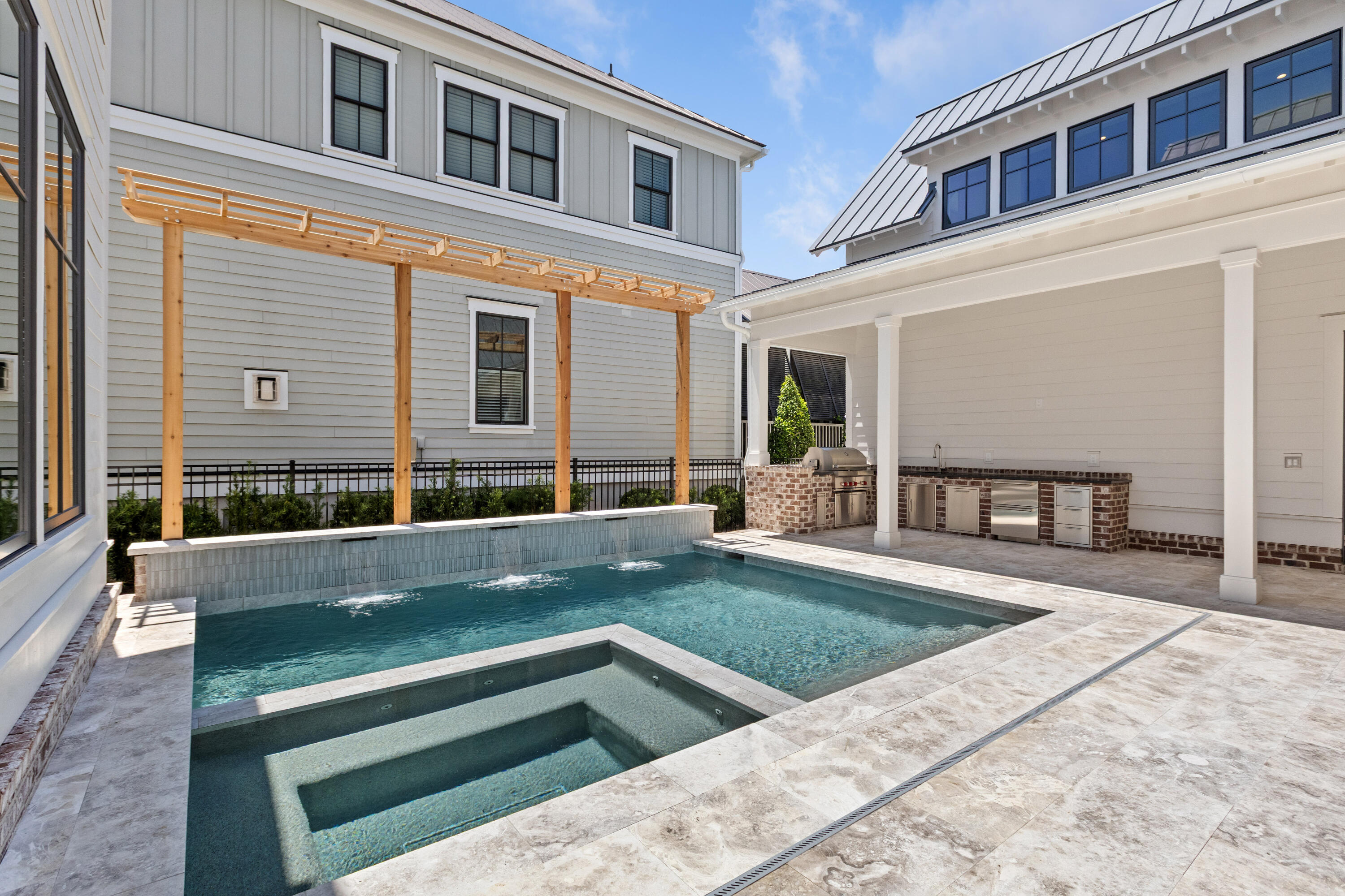 Private pool and spa at 221 Black Powder Lane, with a cedar pergola, a travertine deck, and a covered outdoor kitchen against the grey-shingle facade